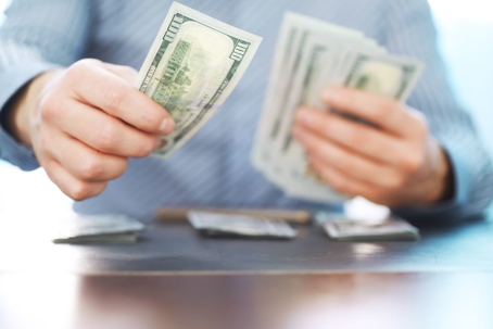 hands counting $100 bills